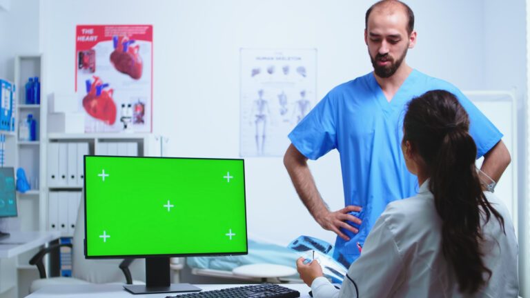 assistant-giving-doctor-x-ray-image-while-working-computer-with-green-screen-monitor-hospital-cabinet-desktop-with-replaceable-screen-medical-clinic-while-doctor-is-checking-patient-radiogra