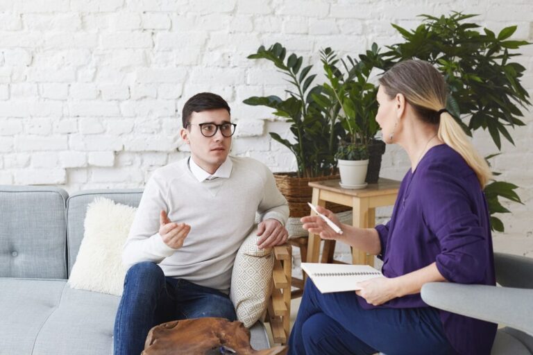 picture-frustrated-young-caucasian-man-wearing-sweater-eyeglasses-sitting-comfortable-couch-sharing-his-personal-problems-with-middle-aged-female-counselor-therapy-session_344912-1930